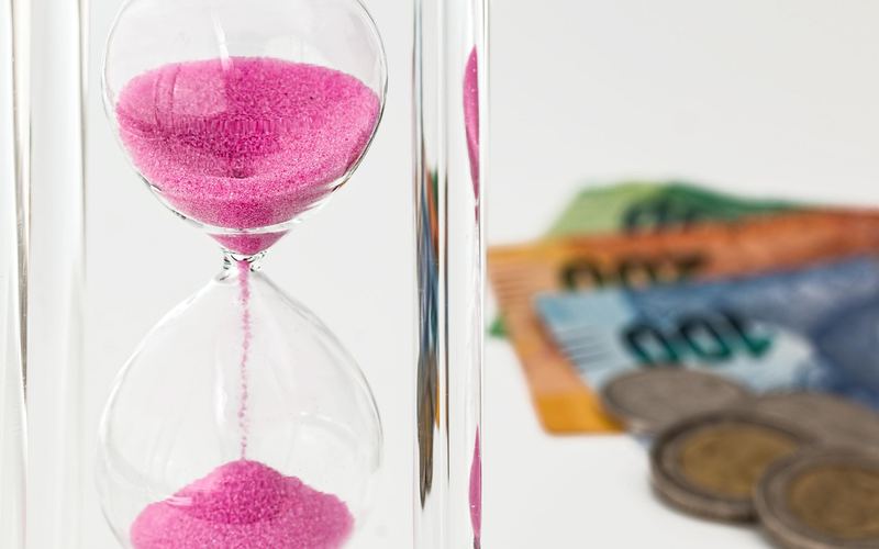 硬貨と紙幣のそばに置かれた砂時計