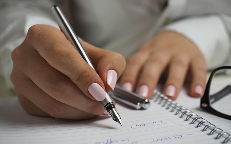ノートに万年筆で書き込む手元